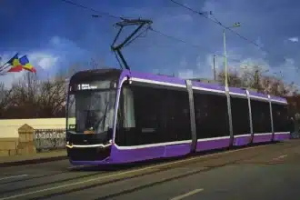 Tramvai modern în Timișoara și afiș cu noile rute temporare de autobuz valabile în perioada lucrărilor din Piața Traian.