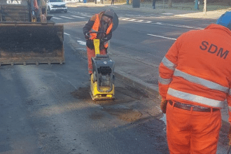 Utilaje de asfaltare și echipe de muncitori efectuând reparații curente pe un drum județean din Timiș.