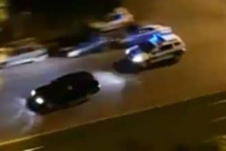 Mașină de poliție cu semnalele luminoase aprinse în urmărirea unui autoturism pe o șosea