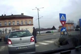 Captură de pe o cameră de bord care surprinde momentul în care un pieton evită la limită un autoturism pe trecere.