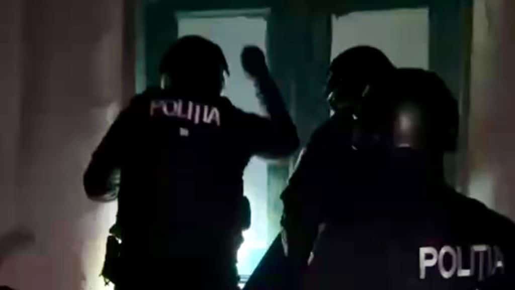 Polițiști din cadrul BCCO Timișoara ridicând unități de stocare și telefoane mobile în cadrul unei investigații de criminalitate informatică.