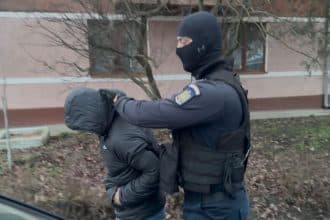 Mascați și anchetatori în fața unei locuințe în timpul descinderilor DIICOT din județul Timiș