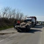 Autoturism cu avarii majore răsturnat pe plafon în afara părții carosabile pe marginea unui drum național.