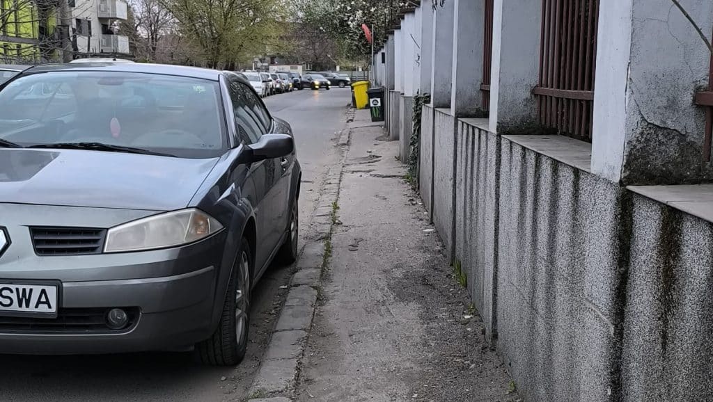 Imagine surprinzând mașini parcate ilegal pe un trotuar îngust din Timișoara, blocând complet accesul pietonilor și al cărucioarelor.