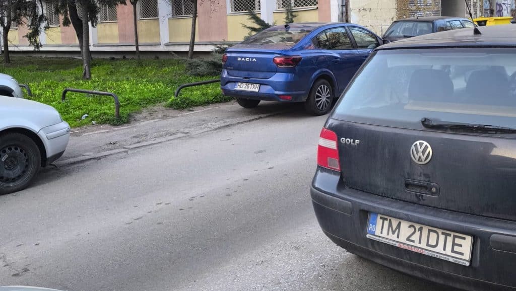 Imagine surprinzând mașini parcate ilegal pe un trotuar îngust din Timișoara, blocând complet accesul pietonilor și al cărucioarelor.