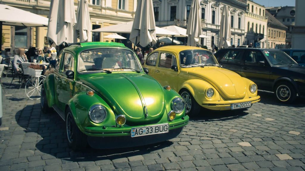 Expoziție de mașini clasice și vehicule istorice de colecție aliniate în fața Domului Romano-Catolic din Piața Unirii, Timișoara.