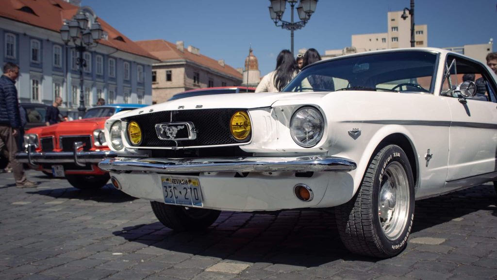 Expoziție de mașini clasice și vehicule istorice de colecție aliniate în fața Domului Romano-Catolic din Piața Unirii, Timișoara.