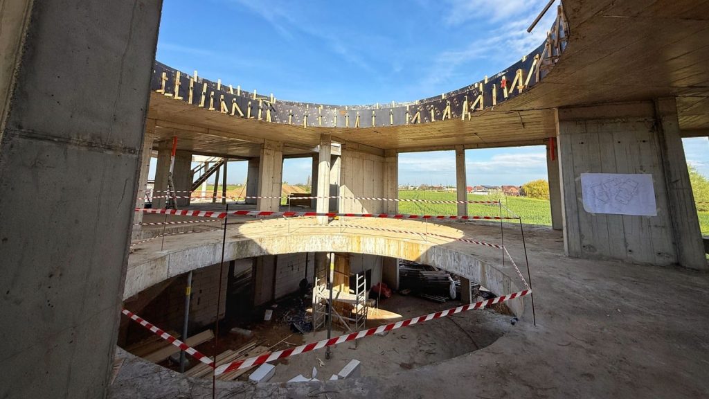 Clădirea modernă a noii grădinițe din Dumbrăvița, aflată în etapa finisajelor, cu spații vitrate mari și structură eficientă energetic.