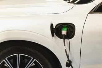 O mașină electrică parcată la o stație de încărcare publică modernă, dotată cu ecran tactil, într-un cartier din Timișoara.