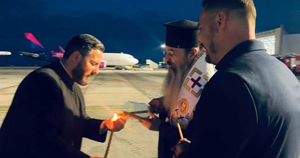 Preoți și reprezentanți ai eparhiilor din vestul țării preluând Lumina Sfântă în felinare speciale de pe pista Aeroportului Internațional Timișoara.