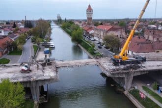 Utilaje masive demontând grinzile de beton ale Podului Muncii de peste canalul Bega din Timișoara.
