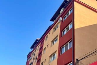 Infografic comparativ al prețurilor pe metru pătrat în Timișoara, Cluj și Brașov pentru apartamente noi și vechi în aprilie 2026.