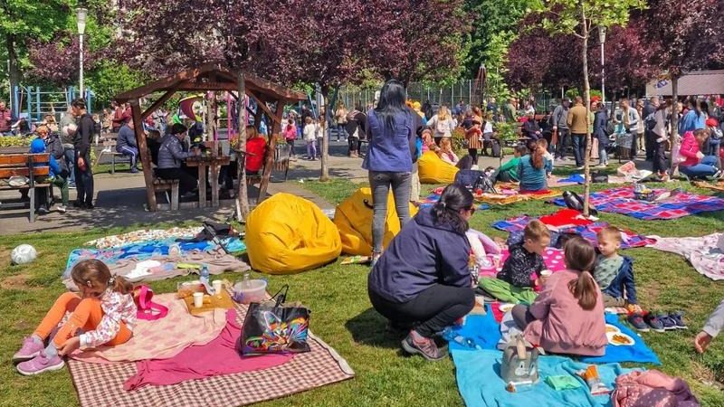 Copii și părinți participând la ateliere creative și spectacole de teatru în aer liber în Parcul Steaua din Timișoara.