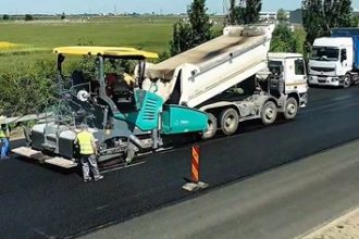 Utilaje de asfaltare și muncitori lucrând la fundația drumului pe Calea Șagului în timpul minivacanței.