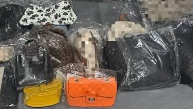 Polițiști verificând articole vestimentare și încălțăminte de brand suspectate a fi contrafăcute într-un magazin din Lupeni.