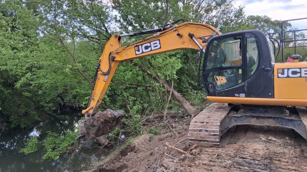Excavatoare de mare tonaj curățând aluviunile și vegetația de pe fundul râului Bega în dreptul localității Balinț.