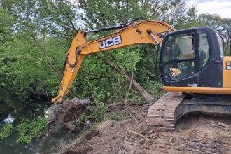 Excavatoare de mare tonaj curățând aluviunile și vegetația de pe fundul râului Bega în dreptul localității Balinț.