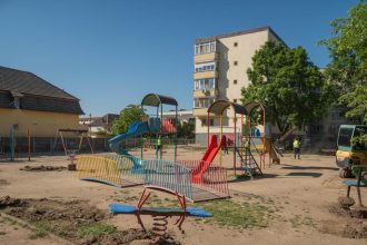 Muncitori lucrând la amenajarea noului loc de joacă de pe strada Orșova din Timișoara, unde se montează echipamente noi și suprafețe de protecție.