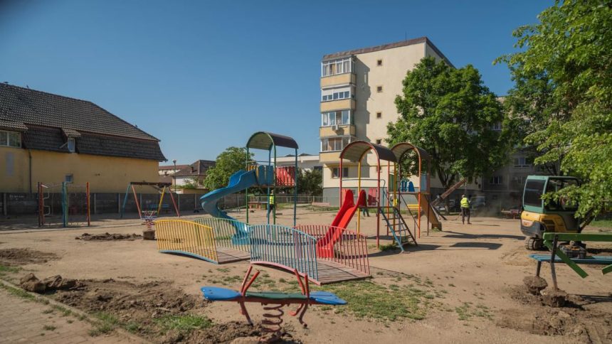 Muncitori lucrând la amenajarea noului loc de joacă de pe strada Orșova din Timișoara, unde se montează echipamente noi și suprafețe de protecție.