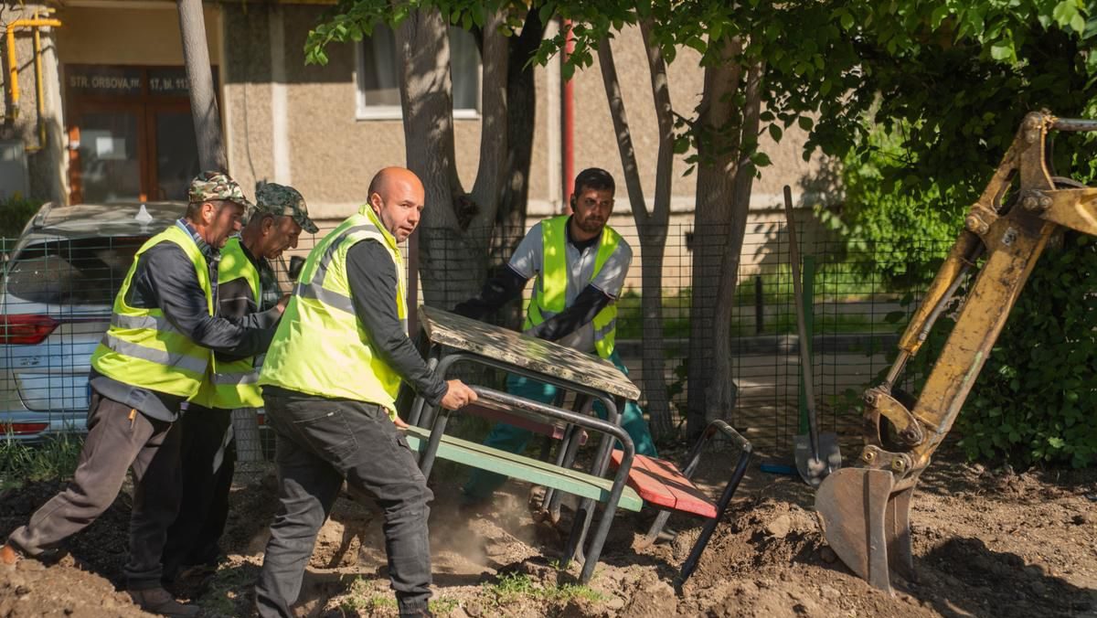 Muncitori lucrând la amenajarea noului loc de joacă de pe strada Orșova din Timișoara, unde se montează echipamente noi și suprafețe de protecție.