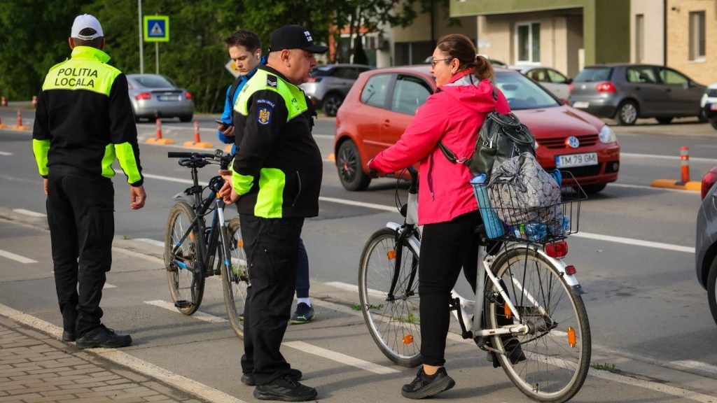 Polițist local din Timișoara verificând echiparea unui biciclist pe Bulevardul Michelangelo.
