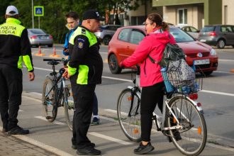 Polițist local din Timișoara verificând echiparea unui biciclist pe Bulevardul Michelangelo.