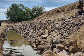 Utilaje ABA Banat executând lucrări de consolidare a malului stâng al râului Timiș la Jabăr pentru stoparea eroziunii lângă dig.
