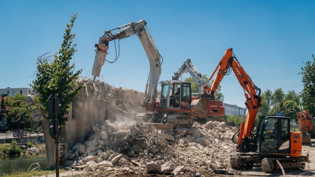 Imagine cu șantierul de la Podul Muncii din Timișoara unde utilajele demontează segmentele vechi de beton deasupra canalului Bega.
