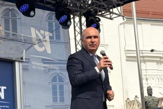 Premierul interimar Ilie Bolojan vorbind pe scenă în fața sutelor de absolvenți ai Universității de Vest din Timișoara adunați în Piața Libertății.