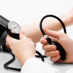 Un cadru medical măsurând tensiunea arterială a unui pacient cu ajutorul unui tensiometru într-un cabinet de cardiologie.