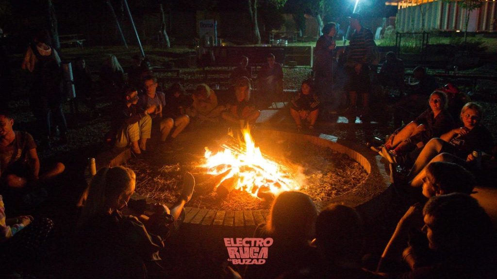 Participanți la festivalul Electroruga din satul Buzad relaxându-se pe iarbă în fața scenei principale de la The Village.