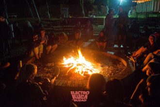 Participanți la festivalul Electroruga din satul Buzad relaxându-se pe iarbă în fața scenei principale de la The Village.