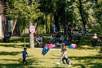 Copii și părinți participând la atelierele interactive organizate în aer liber în Parcul Copiilor din Timișoara.