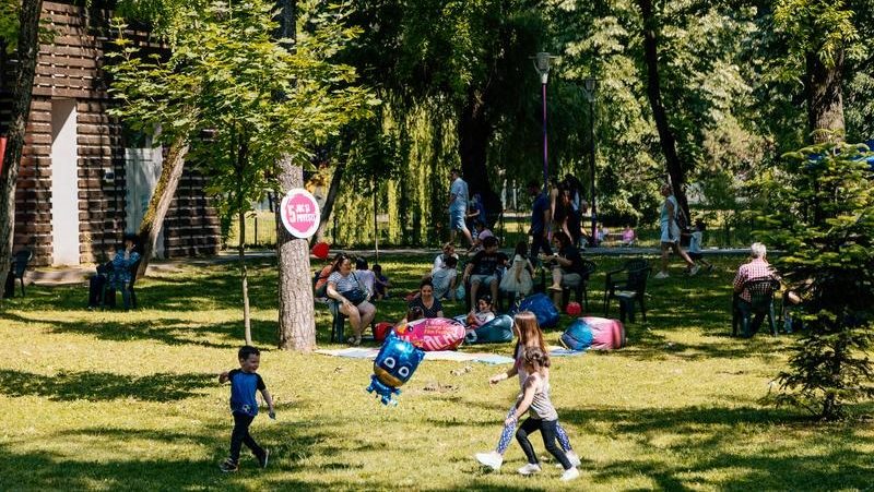 Copii și părinți participând la atelierele interactive organizate în aer liber în Parcul Copiilor din Timișoara.