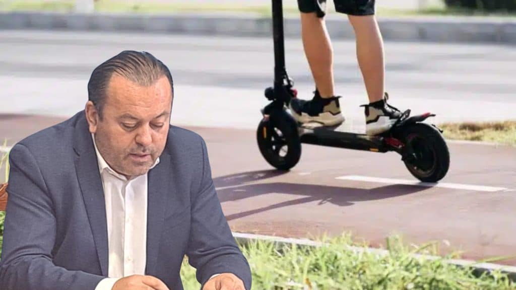 Trotinete electrice parcate pe trotuar în apropierea unei intersecții circulate dintr-un centru urban.
