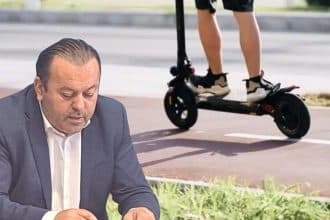 Trotinete electrice parcate pe trotuar în apropierea unei intersecții circulate dintr-un centru urban.