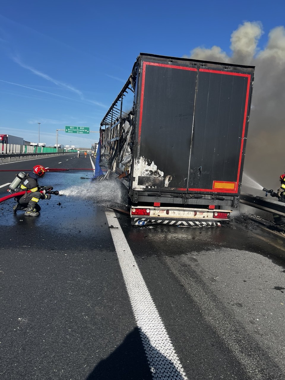 Semiremorcă de autotren cuprinsă de flăcări violente și coloană de fum negru pe banda de urgență a autostrăzii A1.