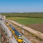 Autocar de transfer pentru călători parcat în fața unei gări CFR din județul Timiș în timpul lucrărilor de reabilitare.