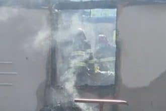 Autospeciale de stingere ale ISU Timiș intervenind cu furtunuri cu apă pentru lichidarea unui incendiu la o casă din mediul rural.