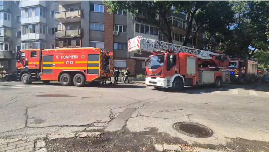 Autospeciale de stingere și autoscară mecanică ale Detașamentului 2 Pompieri Timișoara staționate în fața unui bloc de locuințe.