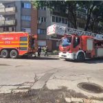Autospeciale de stingere și autoscară mecanică ale Detașamentului 2 Pompieri Timișoara staționate în fața unui bloc de locuințe.