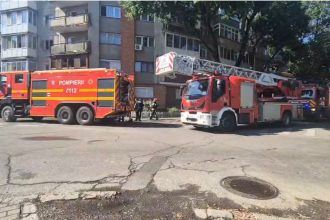 Autospeciale de stingere și autoscară mecanică ale Detașamentului 2 Pompieri Timișoara staționate în fața unui bloc de locuințe.