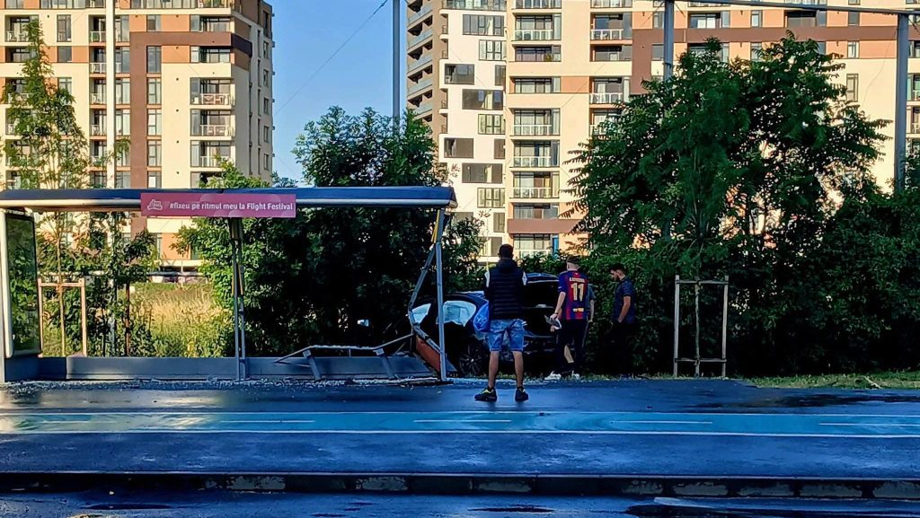 Structura metalică a unei stații de autobuz STPT avariată și geamuri sparte în urma unui impact cu un autoturism.