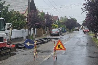 Excavator și utilaje grele efectuând săpături în carosabil pentru montarea unui bazin de canalizare pe o stradă din Dumbrăvița.