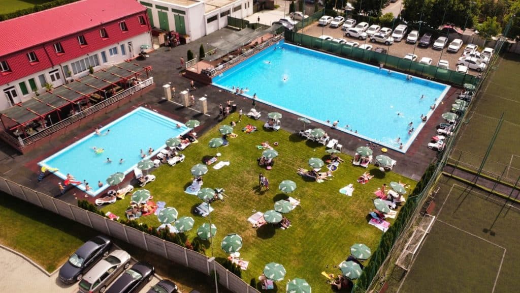 Vedere de ansamblu cu cele două piscine umplute cu apă și zona de șezlonguri pregătite pentru clienți la baza de agrement STPT din Fabric.