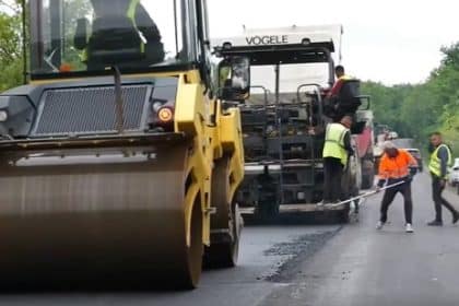 Utilaje grele și finisoare de asfalt turnând un nou strat de rulare pe un sector de drum județean din estul județului Timiș.