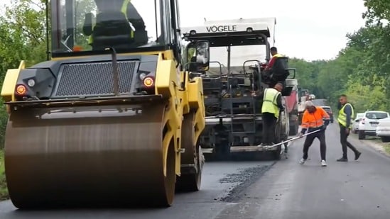 Utilaje grele și finisoare de asfalt turnând un nou strat de rulare pe un sector de drum județean din estul județului Timiș.