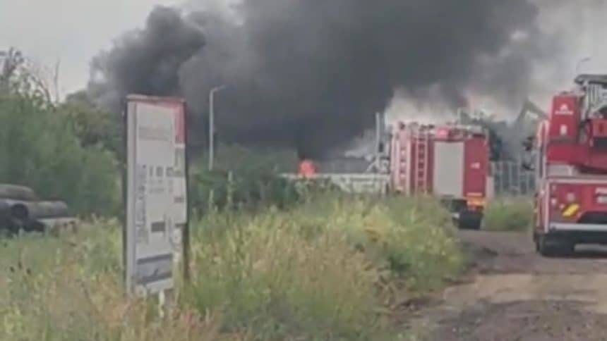 Coloană masivă de fum negru ridicată deasupra șoselei de centură a municipiului Lugoj în timpul incendiului de la hala de piese auto.