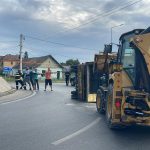Autoutilitară încărcată cu cherestea răsturnată pe o parte într-un sens giratoriu din Moșnița Nouă, cu materialul lemnos împrăștiat pe șosea.