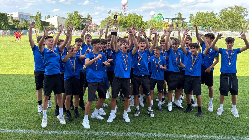 Jucătorii echipei de fotbal juniori U16 ACS Galaxy Timișoara bucurându-se și ridicând trofeul de campioni naționali ai Seriei 7 pe stadionul Electrica.